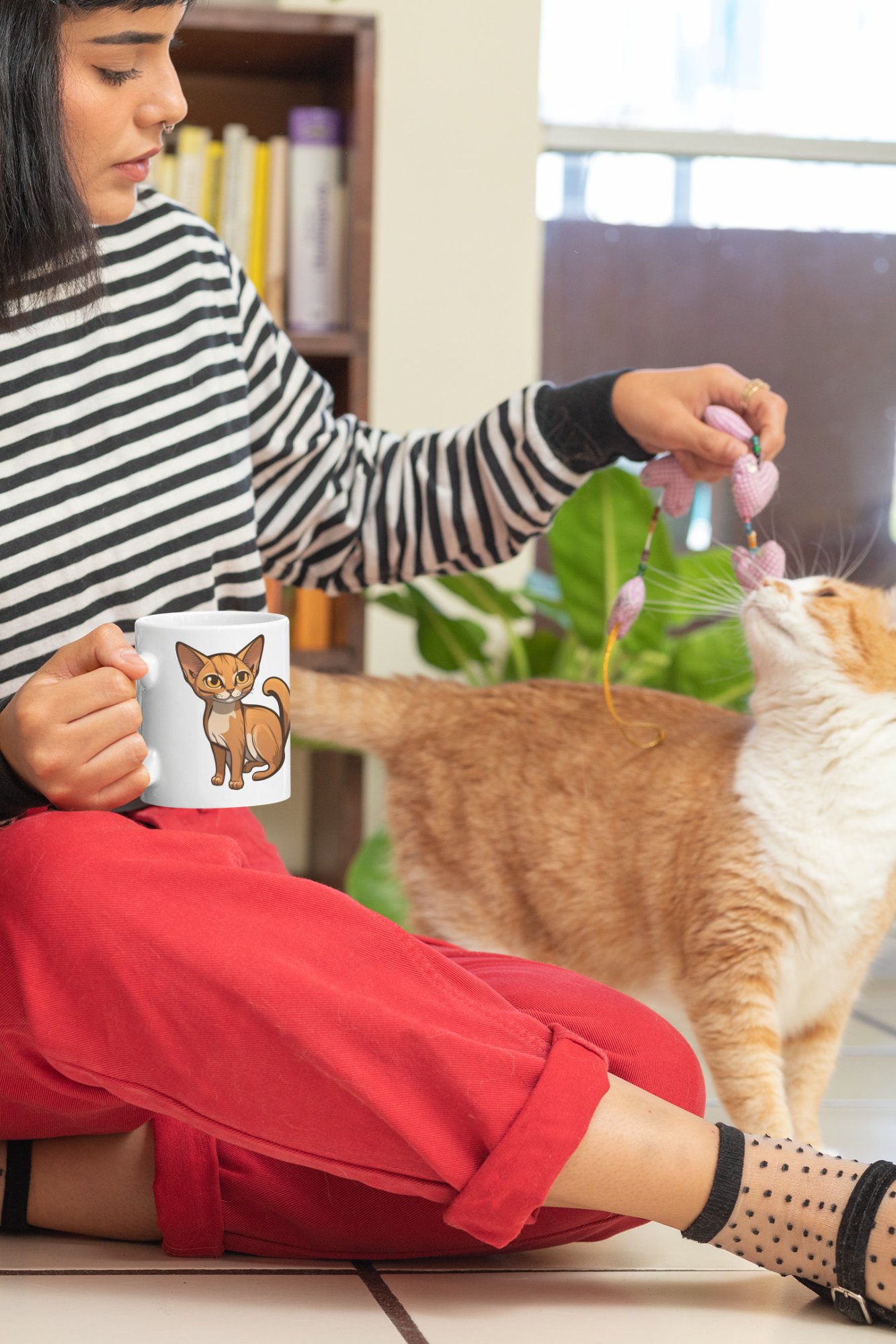Woman holding a Purr-fectly Cat-ffeinated mug while playing with her cat